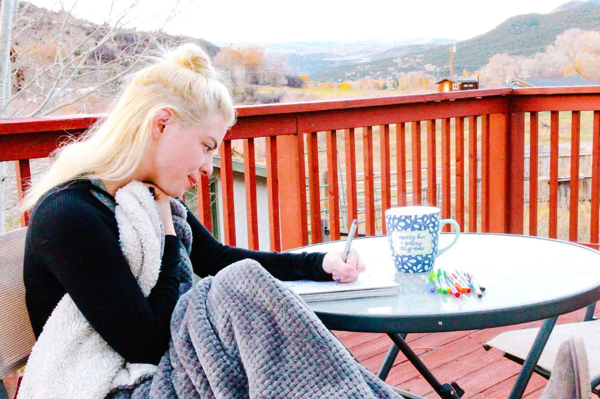 a girl coloring on the porch, which is helping ease her anxiety